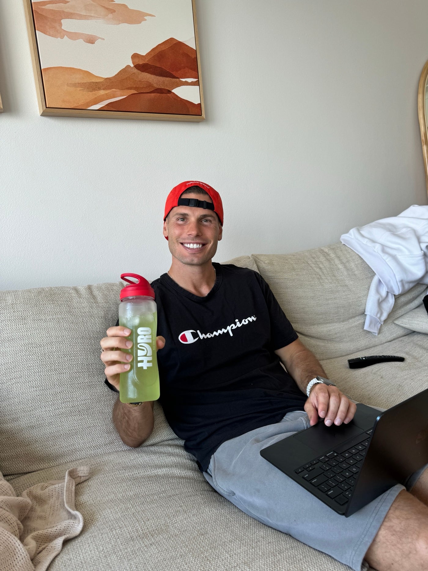 Man on a couch with a laptop and a Hyro bottle filled with lemon-lime drink, working from home