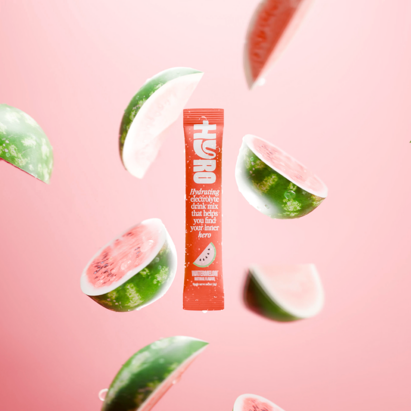 A Hyro watermelon stick suspended in air with floating watermelon slices on a soft pink backdrop